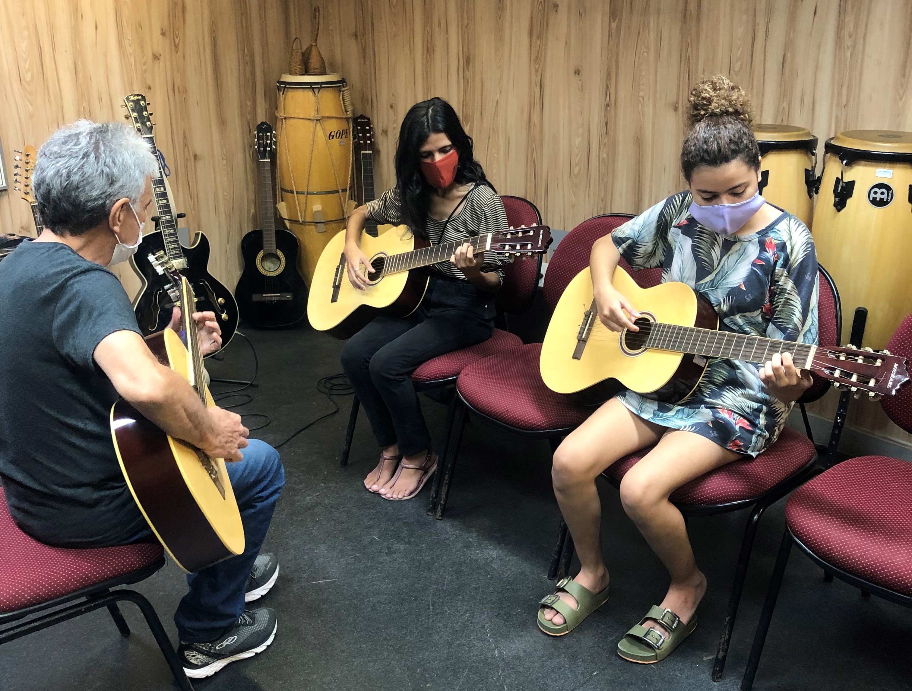 DOIS ALUNOS E O PROFESSOR TOCANDO VIOLÃO 